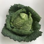 Cavolo nero fresco su un tagliere con utensili da cucina, pronto per essere cucinato.