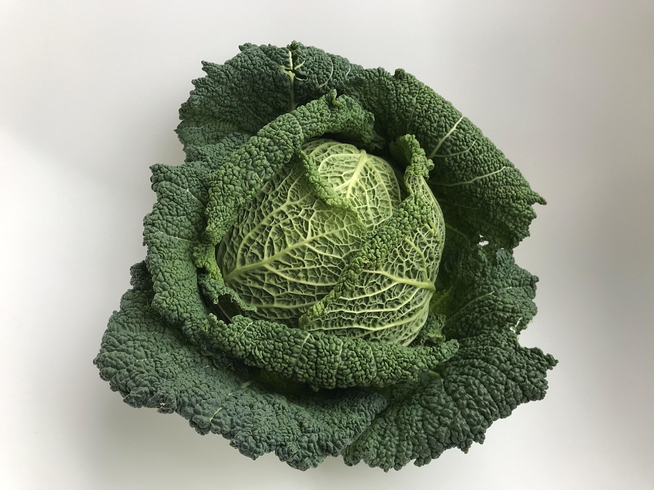 Cavolo nero fresco su un tagliere con utensili da cucina, pronto per essere cucinato.