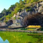 Piscina naturale siciliana circondata da rocce e vegetazione lussureggiante, un vero paradiso estivo.